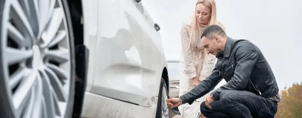 Casal examinando a calota do carro, carro usado