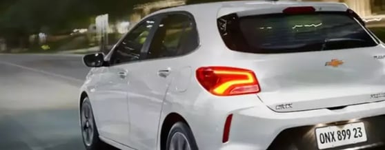 Traseira do Onix branco em movimento na rua