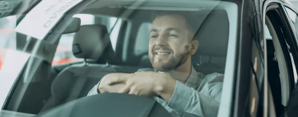 Homem sorrindo dentro do carro