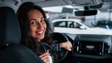 Motorista mulher segurando o volante e olhando para o banco de trás com um sorriso