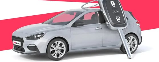 Visão lateral de carro prata com uma grande chave encostada nele