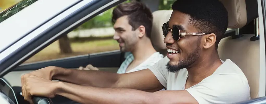 Dois homens sorrindo dirigindo o carro