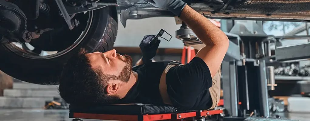 Mecânico embaixo do veículo fazendo manutenção preventiva