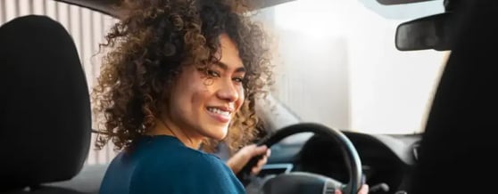 Mulher dirigindo carro e olhando para o banco de trás