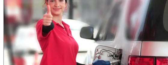Frentista abastecendo carro enquanto olha para a câmera e faz sinal com polegar para cima