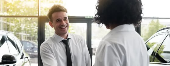 Homem fechando negócio com vendedor em concessionária
