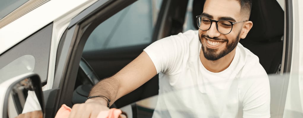Homem sorrindo dentro de carro branco