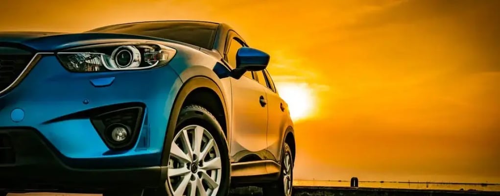 Close nos faróis de um carro com o pôr do sol ao fundo