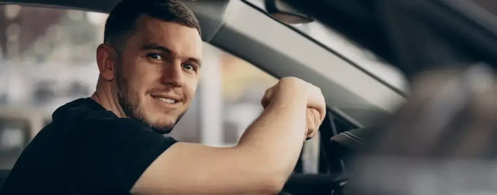 Motorista de aplicativo segurando o volante, dentro de carro