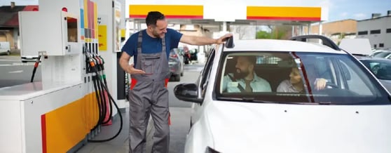 Casal em posto de combustível sendo atendido pelo frentista