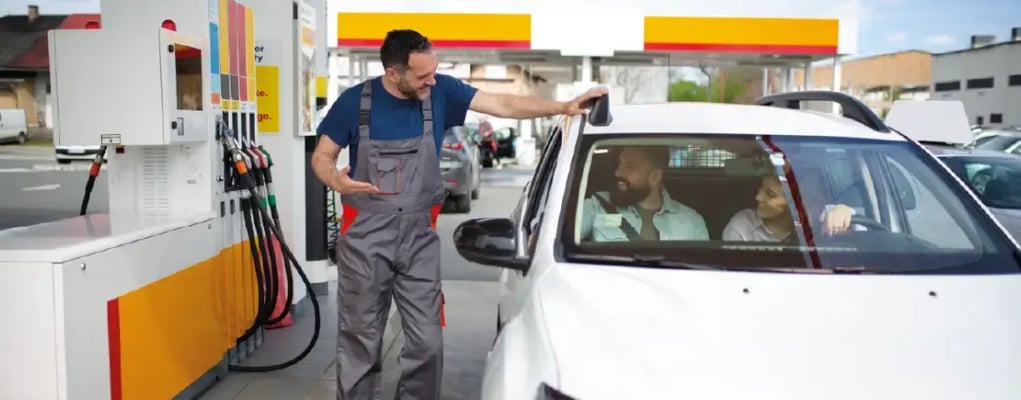 Casal em posto de combustível sendo atendido pelo frentista