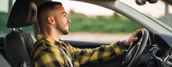 Visão lateral de homem dirigindo o carro alugado na Kovi
