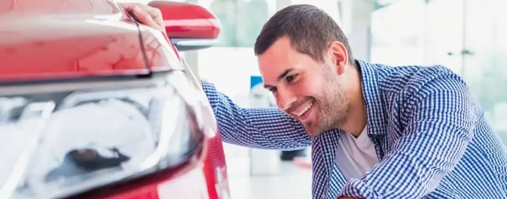 Homem avaliando detalhes do carro zero na loja
