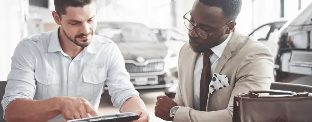 Homens conversando analisando informações sobre um veículo