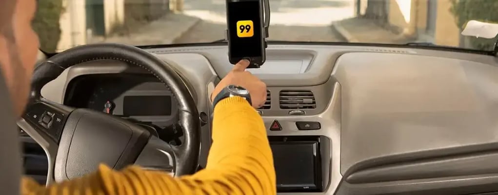 Motorista de aplicativo dentro do carro, iniciando o app da 99