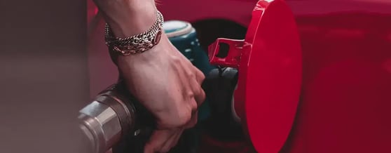 Mão segurando a bomba de gasolina em um carro vermelho