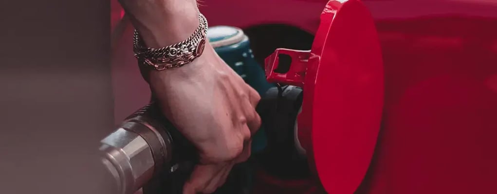 Mão segurando a bomba de gasolina em um carro vermelho