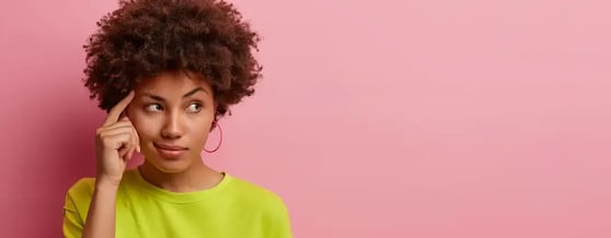 Mulher em fundo rosa com expressão pensativa