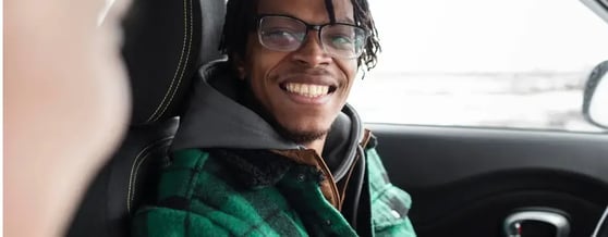 Homem de óculos sorrindo para a câmera de dentro de um carro