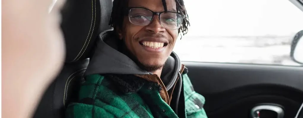 Homem de óculos sorrindo para a câmera de dentro de um carro