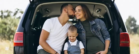 Família feliz sentada no porta-malas do carro