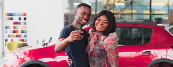 Casal feliz em frente a um carro segurando a chave