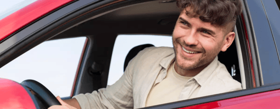 Motorista de aplicativo dentro de um carro vermelho, olhando pela janela