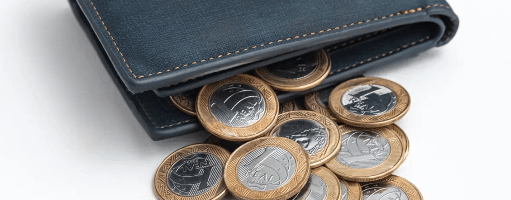 Carteira aberta com várias moedas saindo para fora, economia