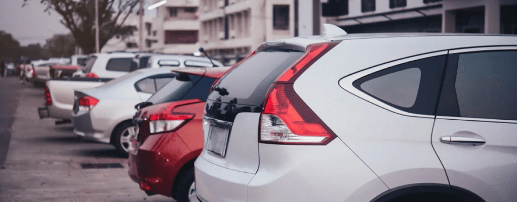 Sequência de traseiras de carros estacionados, mostrando diferentes modelos e cores