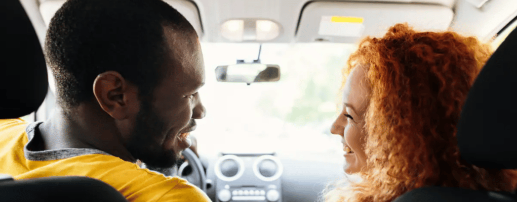 Casal sorrindo dentro do carro