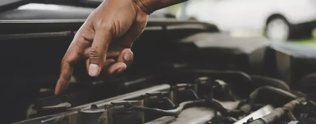 Mão do mecânico apontando para o motor do veículo