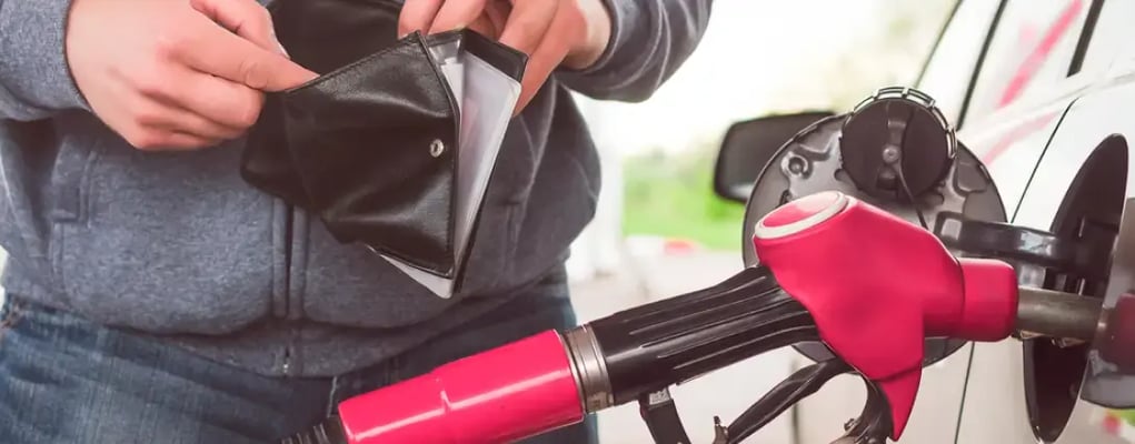 Homem abrindo a carteira enquanto seu carro está sendo abastecido