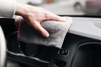 Mão com flanela limpando o interior do carro