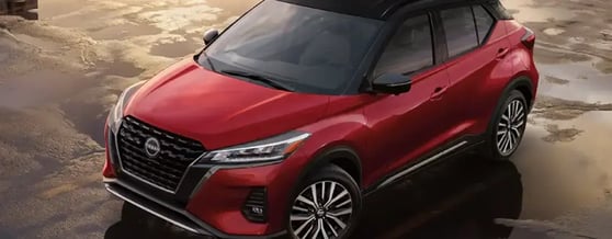 Nissan Kicks vermelho estacionado, refletindo o sol em poças d'água ao redor
