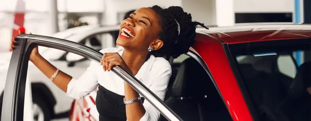 Mulher feliz segurando a porta de seu novo carro