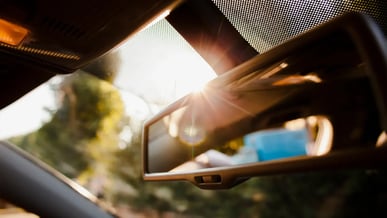 Close no retrovisor de um carro, com a luz do sol sendo refletida