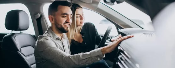 Casal sorridente explorando os detalhes internos do carro