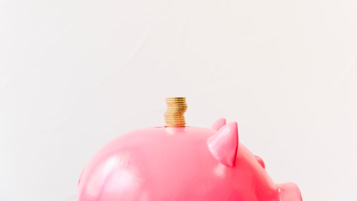 Close de um cofrinho com moedas empilhadas em cima