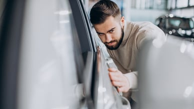 Homem observando atentamente os detalhes externos do carro