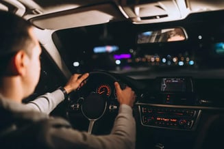 Visão traseira de um motorista dirigindo o carro em uma cidade à noite