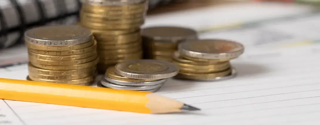 Pilhas de moedas e lápis sobre papel