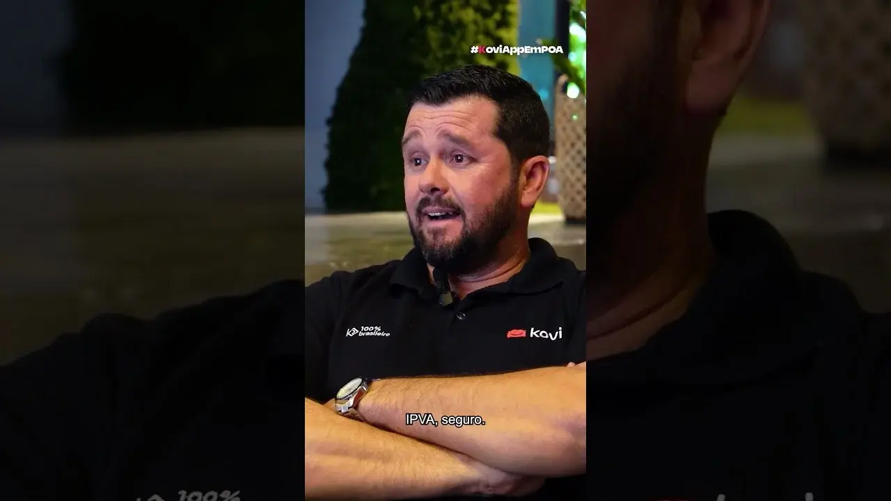 Homem de camisa polo preta com o logo da Kovi e braços cruzados, falando. Legenda: 